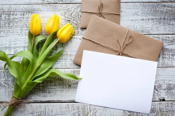 Fresh yellow tulips and empty tag on teal painted wooden background. Selective focus. Place for text. Square image — Stock Photo, Image