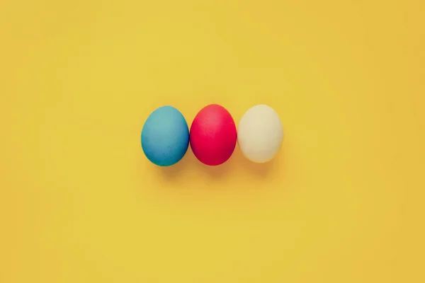 Tre uova di Pasqua colorate fatte a mano isolate su uno sfondo arancione. Con effetto filtro retrò — Foto Stock