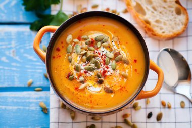 Ahşap bir zemin üzerine krema, ekmek, Yeşiller ve balkabağı tohumları ile ev yapımı balkabağı çorbası. En iyi viev