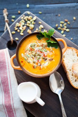 Ahşap bir zemin üzerine krema, ekmek, Yeşiller ve balkabağı tohumları ile ev yapımı balkabağı çorbası. En iyi viev