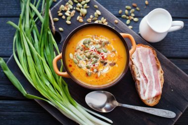 Ahşap bir zemin üzerine krema, ekmek, pastırma ve balkabağı tohumları ile ev yapımı balkabağı çorbası. En iyi viev