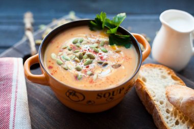 Ahşap bir zemin üzerine krema, ekmek, Yeşiller ve balkabağı tohumları ile ev yapımı balkabağı çorbası. En iyi viev