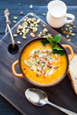 Ahşap bir zemin üzerine krema, ekmek, Yeşiller ve balkabağı tohumları ile ev yapımı balkabağı çorbası. En iyi viev