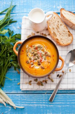 Ahşap bir zemin üzerine krema, ekmek, Yeşiller ve balkabağı tohumları ile ev yapımı balkabağı çorbası. En iyi viev