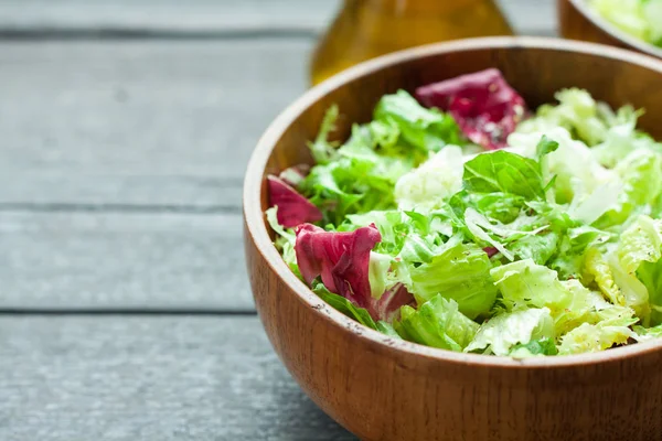 Un plato de frisse de ensalada fresca, Romano y radiccio con aceite de oliva, sal y percec recién molido en un tazón de madera —  Fotos de Stock