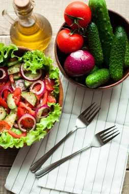 Rustik salata taze domates, salatalık, kırmızı soğan ve marul, ahşap bir kapta zeytinyağı ve karabiber ile giyinmiş. Üstten Görünüm