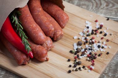 Biberiye ve bir bambu kesme tahtası üzerinde bir kağıt zarf içinde chili biber soslu kuzu ham ev yapımı sosis