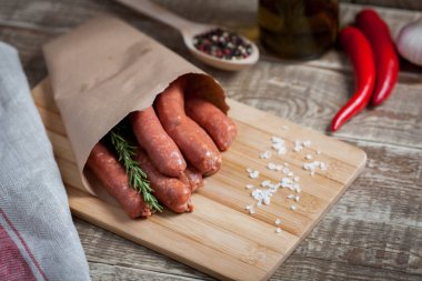 Biberiye ve bir bambu kesme tahtası üzerinde bir kağıt zarf içinde chili biber soslu kuzu ham ev yapımı sosis