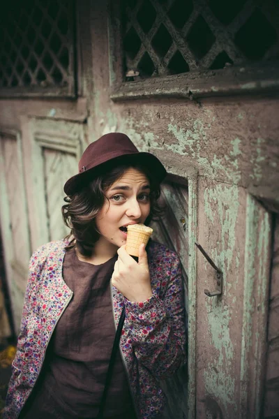 Menina feliz em um chapéu comendo sorvete em um fundo de madeira — Fotografia de Stock