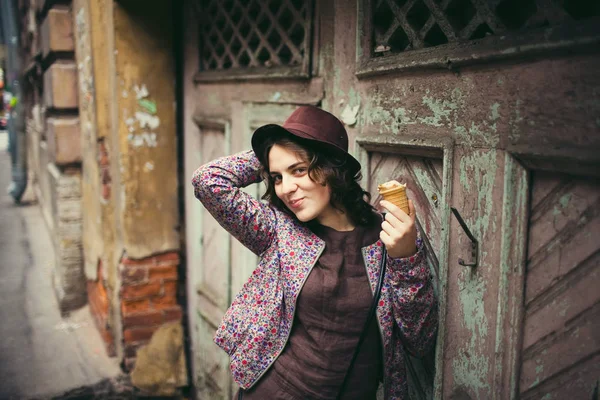 Menina feliz em um chapéu comendo sorvete em um fundo de madeira — Fotografia de Stock
