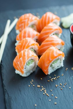 Philadelphia rulo klasik karanlık bir taş zemin üzerine. Somon, Philadelphia peyniri, salatalık, avokado. Japon suşi.