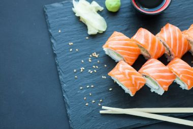 Philadelphia tahtada klasik koyu taş rulo. Somon, Philadelphia peyniri, salatalık, avokado. Japon suşi. Üstten Görünüm