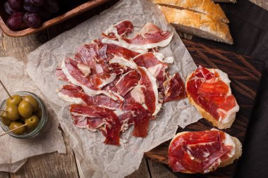 Jamon Iberico beyaz ekmek, zeytin üzerinde kürdan ve ahşap arka plan üzerinde meyve ile. Üstten Görünüm