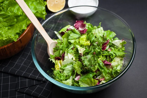 Verse vegetarische salade Meng in een kom helder glas op een zwarte achtergrond. — Stockfoto