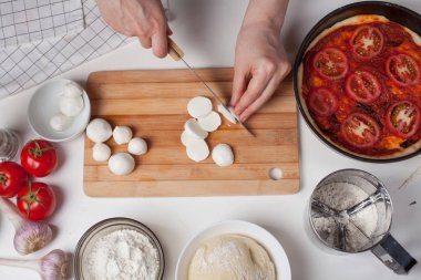 Bir kadın Şef bir İtalyan ev yapımı pizza yapmak için mozzarella peyniri dilimleri. Mozzarella peyniri, pizza hamuru ve sarımsak beyaz masaya vardır