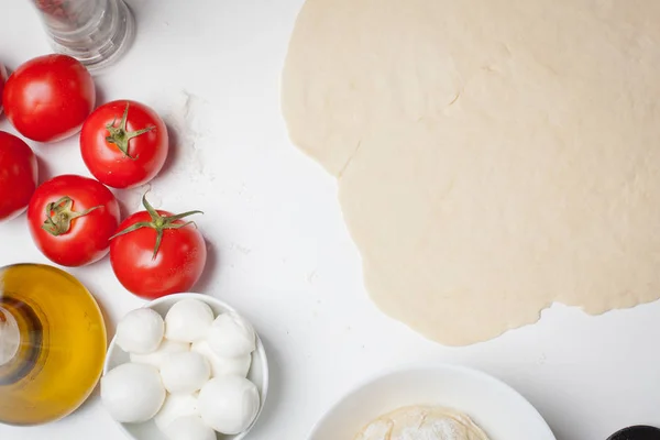 Masa de pizza con ingredientes servidos en una mesa blanca — Foto de Stock