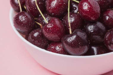 Taze kırmızı kiraz pembe bir arka plan üzerinde beyaz kase. yakın çekim