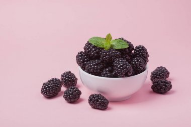 Taze Kırmızı Ahududu pembe bir arka plan üzerinde beyaz bir kase closeup. Kopya alanı