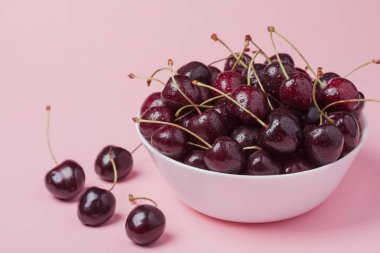 Taze kırmızı kiraz pembe bir arka plan üzerinde beyaz kase. Uzay kopyalayın. yakın çekim