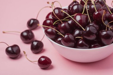 Taze kırmızı kiraz pembe bir arka plan üzerinde beyaz kase. yakın çekim