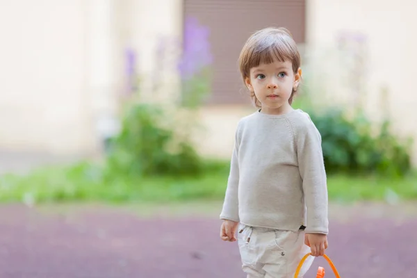 Mały chłopiec piękne długie włosy i niebieskie oczy trzymając wiadro zabawek do piaskownicy — Zdjęcie stockowe
