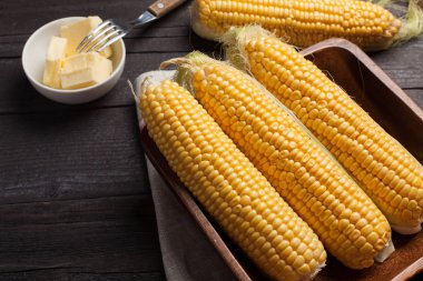 Tuz ve tereyağı ahşap masa, tatlı, üstten görünüm üzerinde taze Mısır. Koyu arka plan