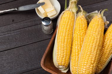 Tuz ve tereyağı ahşap masa, tatlı, üstten görünüm üzerinde taze Mısır. Kopya alanı ile koyu arka plan