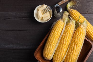 Tuz ve tereyağı ahşap masa, tatlı, üstten görünüm üzerinde taze Mısır. Kopya alanı ile koyu arka plan