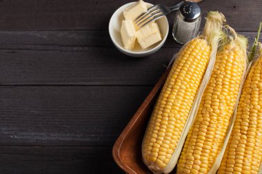 Tuz ve tereyağı ahşap masa, tatlı, üstten görünüm üzerinde taze Mısır. Kopya alanı ile koyu arka plan