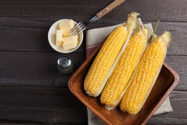 Tuz ve tereyağı ahşap masa, tatlı, üstten görünüm üzerinde taze Mısır. Kopya alanı ile koyu arka plan