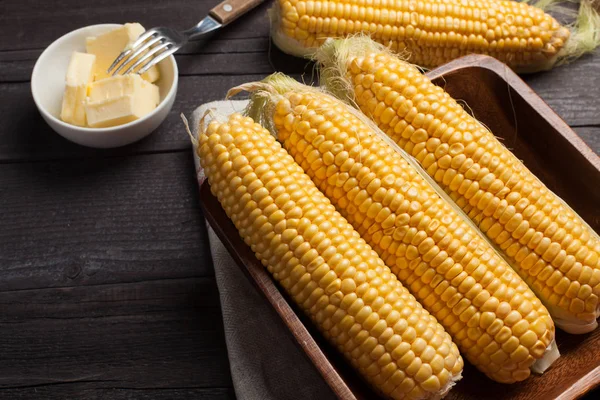 Tuz ve tereyağı ahşap masa, tatlı, üstten görünüm üzerinde taze Mısır. Koyu arka plan