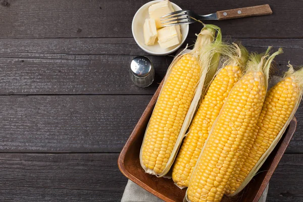 Tuz ve tereyağı ahşap masa, tatlı, üstten görünüm üzerinde taze Mısır. Kopya alanı ile koyu arka plan