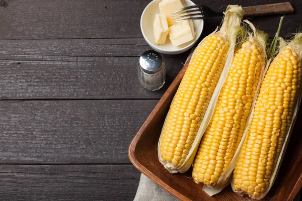 Tuz ve tereyağı ahşap masa, tatlı, üstten görünüm üzerinde taze Mısır. Kopya alanı ile koyu arka plan