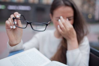 Gözlük el ile çekici erkek portre portre. Zavallı genç kız görme ile ilgili sorunlar vardır. O onun burun ve yorgunluğu gözlerinden losyonları. Bir öğrenci çalışma ve kitap okumak için yorgun