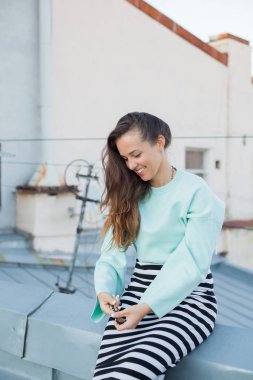 Kahverengi gözlü güzel kız eski şehrin bir çatıda oturan saç düzeltiyor