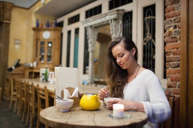 Sarı demlik çay içme bir kafede oturan çekici ve yalnız kız