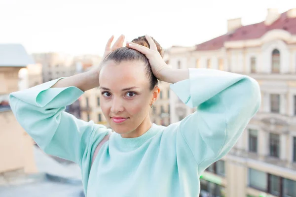 Bella ragazza con i capelli castani, raddrizza i capelli, in piedi sul tetto della casa nel centro storico — Foto Stock