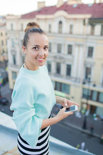 Mulher de negócios bonita mensagens com clientes no telefone e sorrindo enquanto estava no telhado da casa na cidade velha — Fotografia de Stock