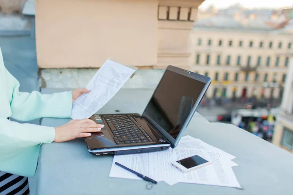 Close-up de mãos de menina de negócios que entra em dados do documento para o laptop de pé no telhado da casa — Fotografia de Stock