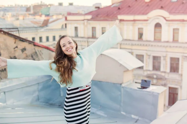 Porträt eines schönen jungen Mädchens, das abends auf den Dächern der Altstadt spaziert. das Konzept der Freiheit. sie steht mit den Armen an den Seiten — Stockfoto