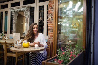 Akşam bir bardak çay ile parlak ve sıcak kafede oturan ve pencereden dışarı bakıp genç çekici kız. Karanlık ve soğuk sokaktır. Konfor kavramını