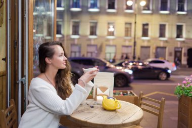 Akşam bir bardak çay için geçen arabalar ve şehir hayatı zemin ile bir kafede oturan genç çekici kız
