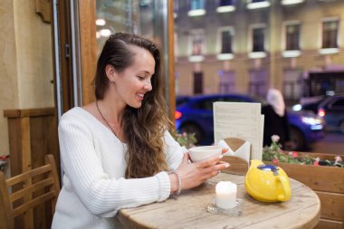 Akşam bir bardak çay için geçen arabalar ve şehir hayatı zemin ile bir kafede oturan genç çekici kız