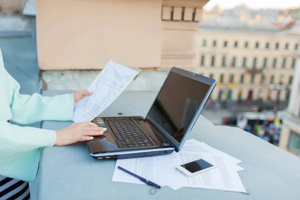 Nahaufnahme der Hände einer Geschäftsfrau, die Daten aus dem Dokument in den Laptop auf dem Dach des Hauses eingibt — Stockfoto