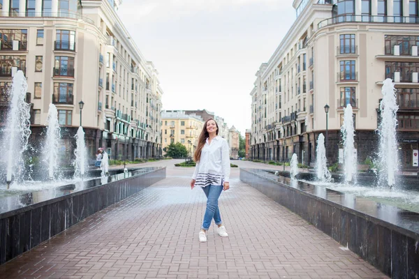 Młoda i piękna dziewczyna idzie przez fontanny i uśmiechając się w nowym kompleksie mieszkaniowym — Zdjęcie stockowe