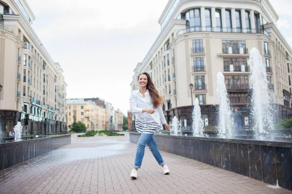 Fiatal és gyönyörű lány sétál a szökőkút, és mosolyogva egy új lakópark — Stock Fotó