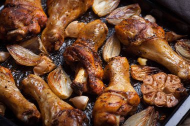 Fırında tavuk bacak çeyrek soğan, sarımsak ve biber koyu arka planı portre üzerinde. Üstten Görünüm