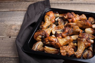 Fırında tavuk bacak çeyrek soğan, sarımsak ve biber koyu arka planı portre üzerinde. Üstten Görünüm