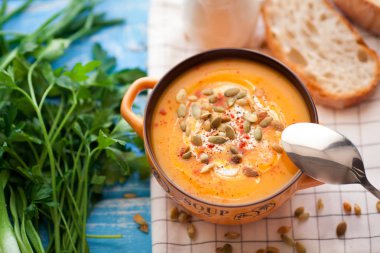 Ahşap bir zemin üzerine krema, ekmek, Yeşiller ve balkabağı tohumları ile ev yapımı balkabağı çorbası. Üstten Görünüm