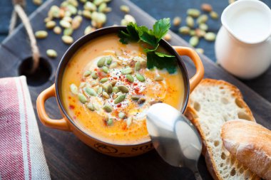 Ahşap bir zemin üzerine krema, ekmek, Yeşiller ve balkabağı tohumları ile ev yapımı balkabağı çorbası. En iyi viev